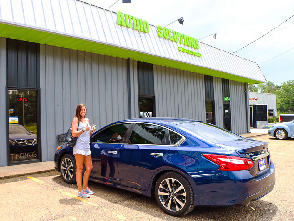 Photo of Audio Solutions and Accessories storefront with girl posing in front of sedan